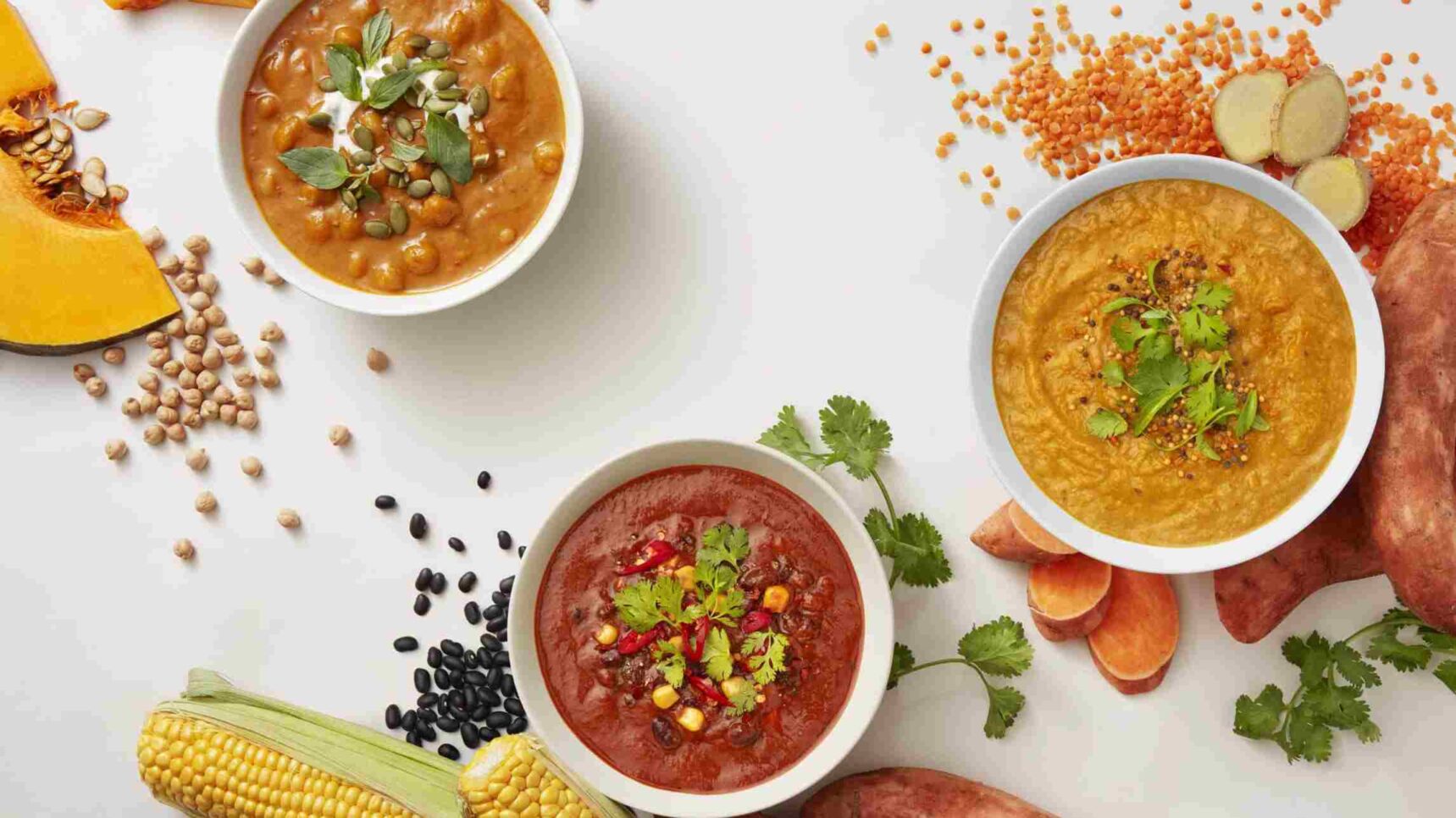 Colorful and flavorful soup bowls by reborn digital marketing agency - reborn - digital creative agency in sydney Three delicious bowls of soup, featuring a variety of colorful ingredients such as lentils, chickpeas, and spices, surrounded by fresh vegetables like sweet potatoes and corn. This image may represent a vibrant food campaign or a cooking project promoted by Reborn Digital Marketing Agency.