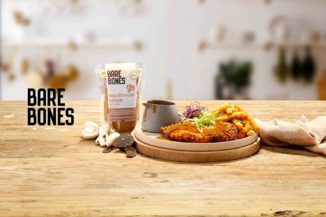A delicious plate of food featuring a crispy chicken dish with mushroom sauce, paired with fries, alongside a package of Bare Bones Mushroom Sauce. The scene exudes freshness, showcasing a culinary experience that reflects the theme of "Reborn Digital Marketing Agency" through innovative and fresh approaches.