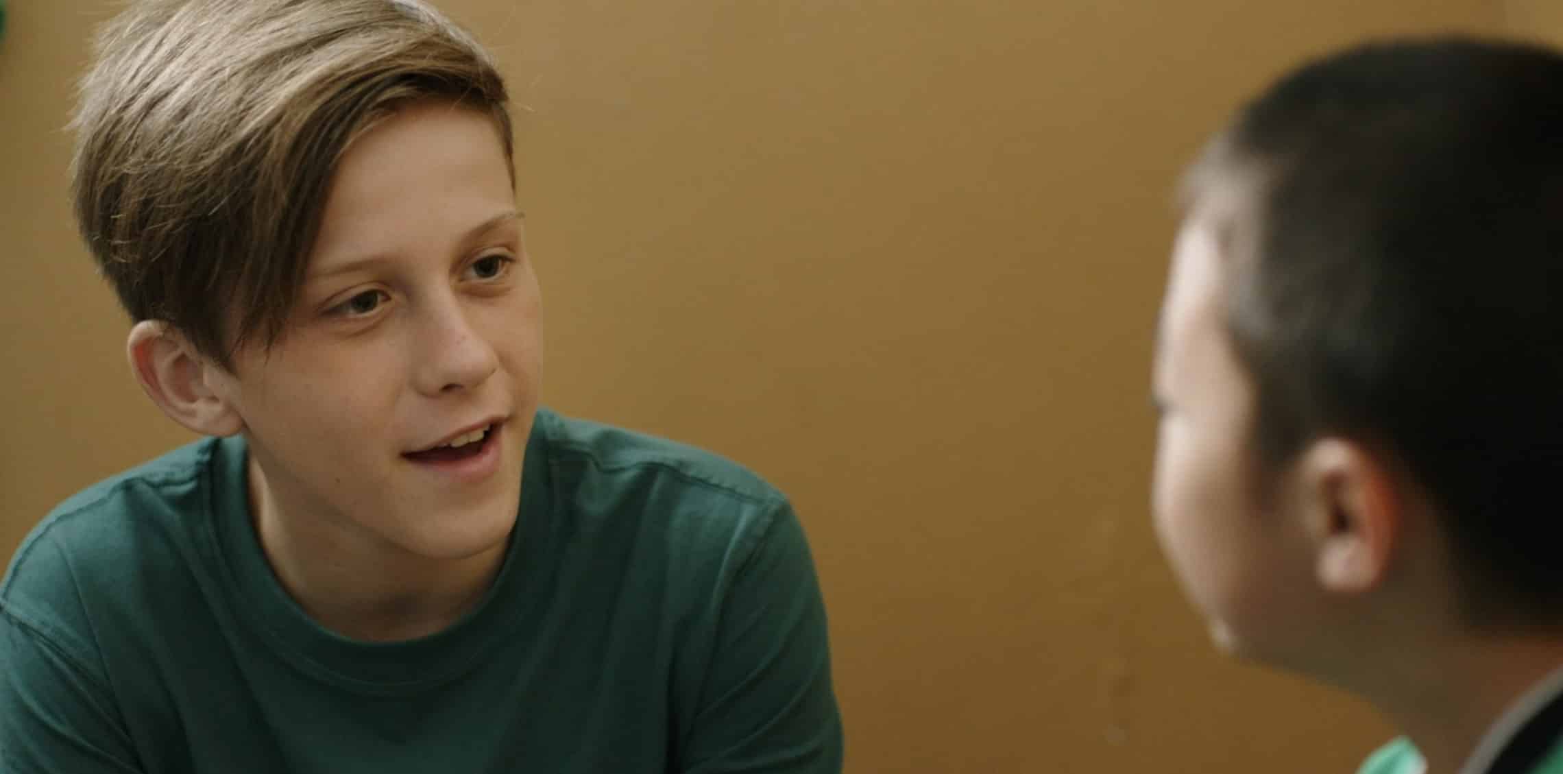 A young boy smiling and talking to another child, illustrating empowerment and mentorship in youth-focused initiatives.