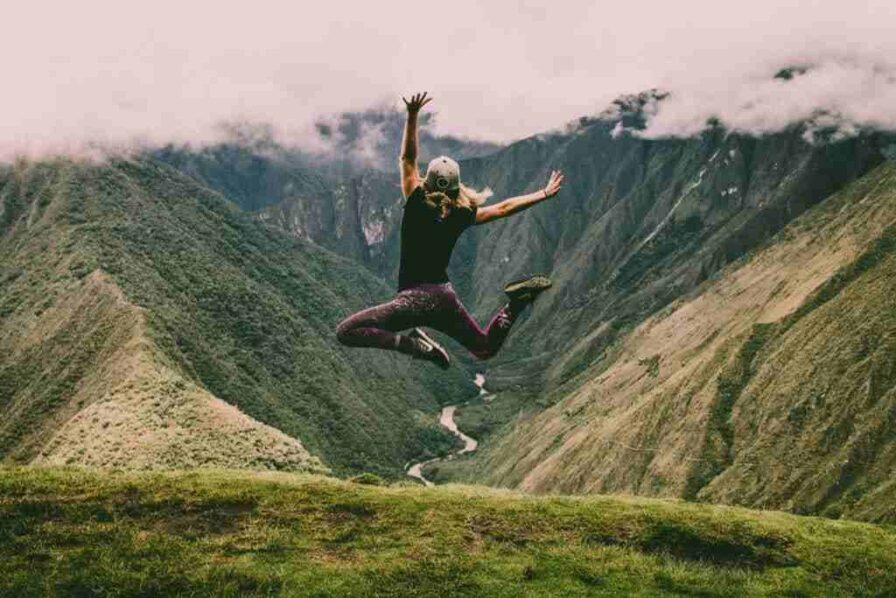 Woman jumping at the peak of a mountain